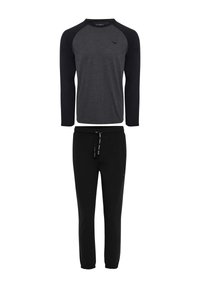 Pantalones de chándal negros con puños elásticos, combinados con una camiseta de manga larga gris que presenta mangas raglán negras y un pequeño logo.