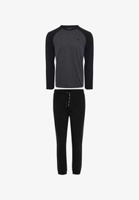 Pantalones de chándal negros con puños elásticos, combinados con una camiseta de manga larga gris que presenta mangas raglán negras y un pequeño logo.