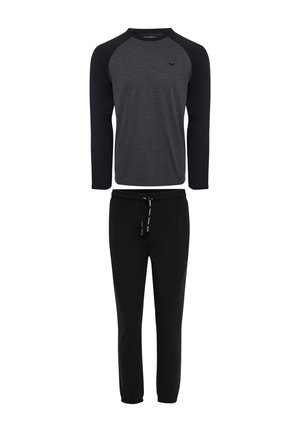 Pantaloni della tuta neri con polsini elastici abbinati a una maglietta grigia a maniche lunghe con maniche raglan nere e un piccolo logo.