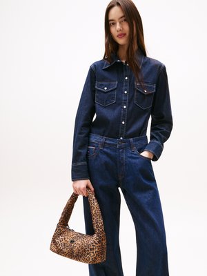 Chemise en denim avec col pointu et deux poches poitrine, associée à un jean bleu à jambes larges. Tenue d'un sac à main en imprimé léopard marron.