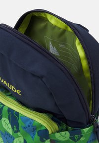 Compacte rugzak met een groen bladmotief, marineblauwe accenten en een ritssluiting. Interieur met een heldergroene voering en naamlabel.