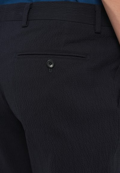 Pantaloni de culoare bleumarin închis, confecționați dintr-un material texturat. Prezintă un buzunar posterior cu închidere cu un singur nasture negru și un design curat, croitorit.