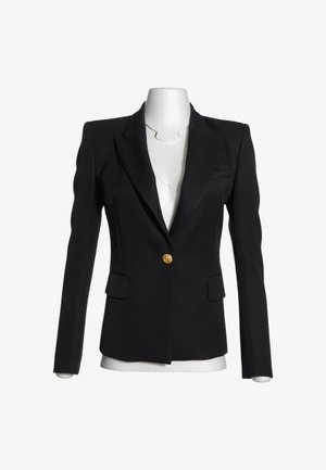 Blazer negro a medida con un solo botón dorado, solapas con muesca y dos bolsillos delanteros con solapa, mostrado en un maniquí blanco sin cabeza.