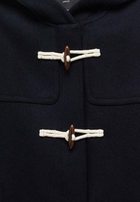Manteau bleu marine foncé avec deux fermoirs à corde blanche et des boutons en bois marron sur la fermeture centrale avant.