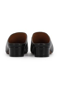 Mules en cuir noir avec un petit talon bloc, présentant une texture lisse et un design à dos ouvert. L'intérieur est marron avec un détail de couture simple.