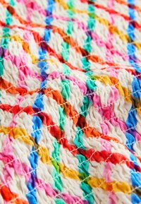 Gros plan d’un tissu texturé avec un motif ondulé multicolore comprenant des nuances de rose, orange, bleu, vert, jaune et blanc.