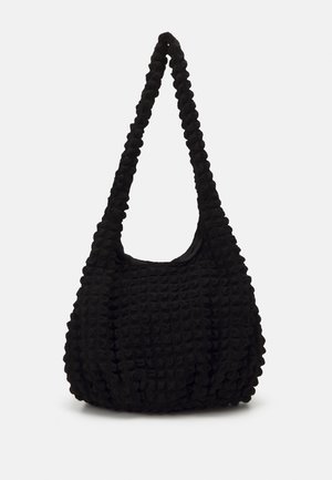 Sac à main noir en tissu texturé façon gaufré avec une large bandoulière, présenté sur un fond clair uni.