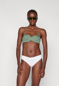 Grønn bandeau bikini topp paret med hvit bikini bunn, med en vridd design i midjen. Jevn tekstur, minimalistisk stil.
