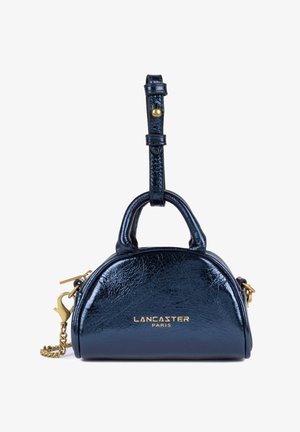 Sac à main en cuir noir brillant avec quincaillerie dorée. Présente une forme arrondie, des poignées supérieures doubles et une bandoulière en chaîne détachable. Logo doré visible.