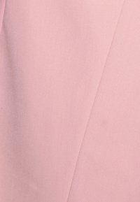 Tissu rose pâle avec une texture lisse, présentant des coutures diagonales pour un détail supplémentaire. Aucun motif ni accent additionnel visible.