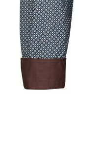 Pantaloni in tessuto a fantasia con un risvolto marrone scuro. Il colore di base è blu navy con piccoli disegni geometrici bianchi e blu.