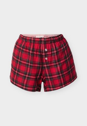 Rdeče-črne karo bombažne bokser hlačke z elastičnim pasom in dvema gumboma spredaj, položene na ravno belo podlago.