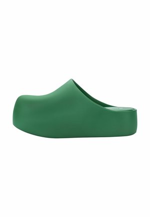 Zueco verde sólido con plataforma, tipo slip-on, con puntera cerrada y redondeada y suela gruesa elevada, visto de lado sobre un fondo blanco.