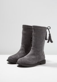 Bottes en suédine grises mi-mollet avec fermeture éclair sur le côté, détails cousus, semelle noire et débardeur décoratif à la boucle arrière.