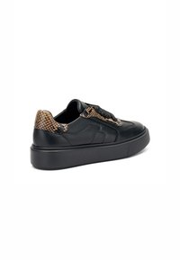 Zapatillas de cuero negro con un talón marrón texturizado y con patrón. Presentan una puntera redondeada, suela gruesa y cordones negros, diseñadas para uso casual.