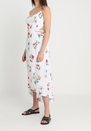 Florales Midikleid in Weiß mit verstellbaren Spaghettiträgern, seitlichen Ausschnitten und einem Saum mit hoher und niedriger Länge. Mit roten und gelben Blumenmustern.