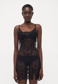 Zwart kanten lingerie set met doorschijnend bloemenpatroon, verstelbare bandjes en zijsplitdetail. Zachte, delicate stof en intricate kanten accenten.