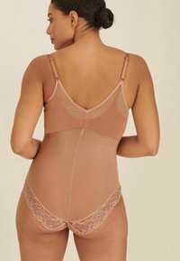 Nudefarbener Bodysuit mit verstellbaren Trägern, Spitzenbesatz im Rücken, glatter Stoffstruktur und einer taillierten Passform, die eine elegante Silhouette präsentiert.