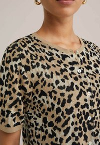 Cardigan à motif léopard en beige et noir, fabriqué en tricot, avec un col rond et une fermeture à boutons.