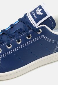 Blue leather sneaker with white stitching, perforations, and matching laces. Branding on tongue and side; rubber outsole for durability.