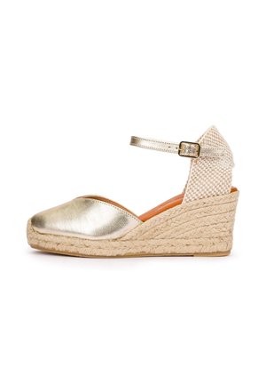 Wedge espadrille sandal with metallic gold closed toe, braided jute sole, woven back heel, and adjustable ankle strap with gold buckle.