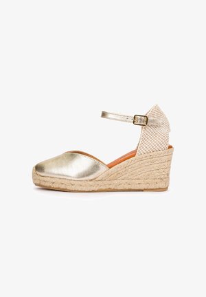Wedge espadrille sandal with metallic gold closed toe, braided jute sole, woven back heel, and adjustable ankle strap with gold buckle.