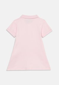 Φόρεμα πόλο σε ανοιχτό ροζ βαμβάκι, με γιακά και κοντά μανίκια. Λείο ύφασμα με ίσια, ελαφρώς φαρδιά λαιμόκοψη.