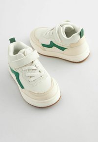 Hvide sneakers med grønne accenter, med en struktureret overdel, snørebånd og velcro lukning, og en gummisål. Rundet tådesign.