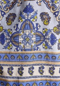 Puuvillane kangas, millel on sinine ja kollane lilleline muster koos geomeetriliste aktsentidega. Sisaldab keerukaid kujundusi ja piiritletud sektsioone erinevates laiuses.