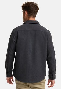 Dark gray wool shirt with a collared neck, long sleeves, and buttoned cuffs. Features a textured fabric and a slightly curved hemline.