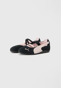 Black and blush pink sports shoes with a soft suede upper, strap design, round toe, and textured black rubber sole featuring a logo detail.