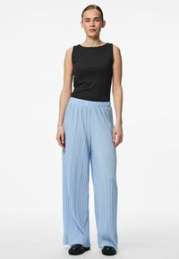 Svart ärmlös topp matchad med ljusblå, plisserade byxor med vida ben och svarta skor, med en avslappnad passform och elastisk midja.