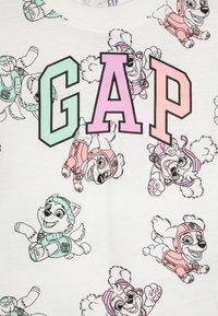 Bílá mikina s veselými kreslenými psy v pastelových barvách. Logo "GAP" v mátové a růžové barvě je výrazně zobrazeno. Měkký bavlněný materiál.
