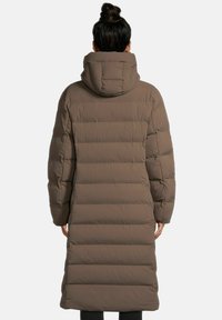 Langer brauner Puffer-Mantel mit hohem Kragen und figuriertem Schnitt. Verfügt über horizontale Steppabschnitte und eine Kapuze. Der Stoff sieht glatt aus.