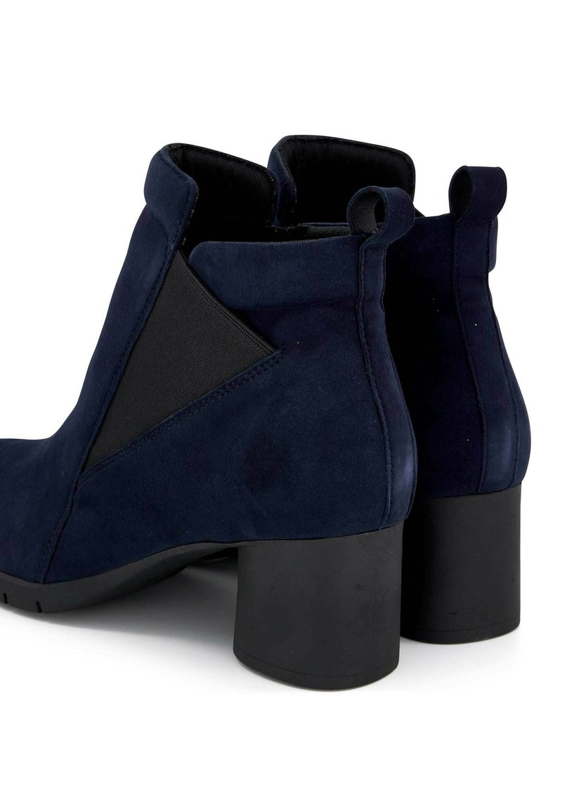 Bottines en suède bleu marine avec un panneau élastique noir géométrique, un talon carré arrondi et des languettes pour un enfilage facile.