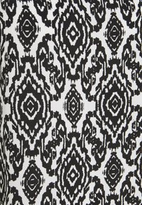 Czarnobiała tkanina w wzory, z odważnym, abstrakcyjnym designem, zawierającym kształty diamentów i owali, tworząca uderzającą teksturę wizualną.