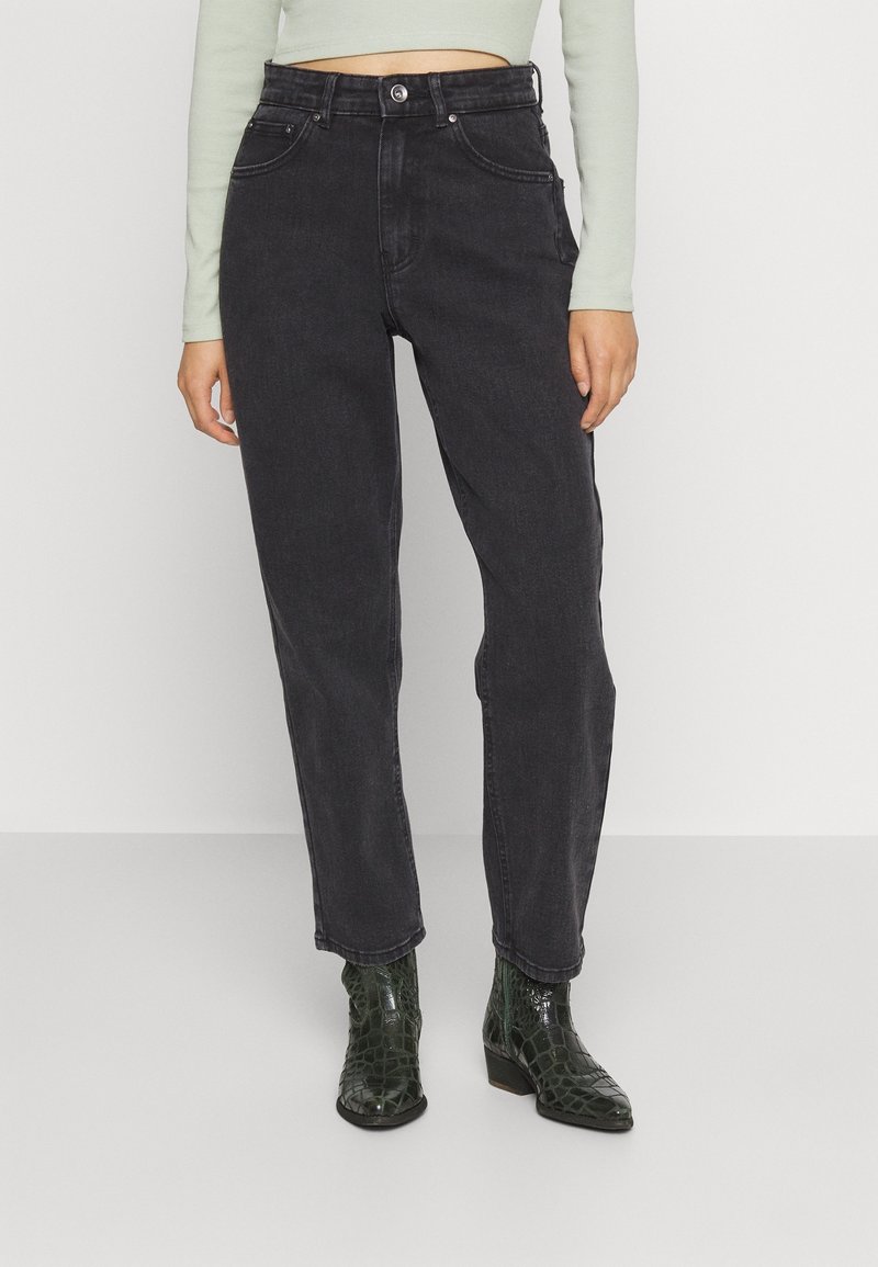 Svarta högmidjade jeans med fem fickor, ljusa sömmar och rak benpassform. Matchas med strukturerade gröna ankelstövlar.