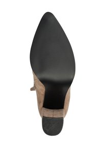 Zapato de tacón alto de ante beige con puntera afilada y suela de goma negra texturizada, con un diseño elegante y detalles de costura sutiles.