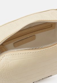 Beige croc-embossed leather pouch with silver zipper, showing interior zip pocket and Valentino brand label inside.