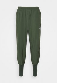 Dunkelgrüne Sporthose mit elastischem Bund, schmal zulaufenden Bündchen und seitlichen Taschen. Das Material wirkt weich, glatt und leicht.
