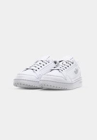 Zapatillas blancas de cuero con acentos perforados, puntera redonda, diseño con cordones y suela de goma texturizada que presenta un patrón de relieve.