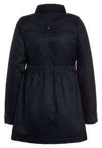 Manteau mi-long bleu marine avec une taille cintrée, des accents de boutons et un tissu doux et texturé. Doté d'un col classique et de manches longues.