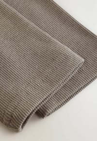 Ribb-vävt tyg i en mjuk, dämpad brun färg, med rena kanter och prydlig sömnad, samt en strukturerad yta och vikt design.