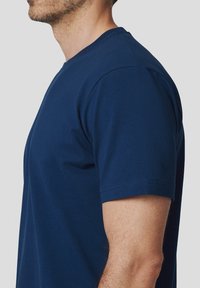 Granatowa bawełniana koszulka z klasycznym krojem, krótki rękaw i żeberkowy dekolt. Gładka tekstura bez widocznych wzorów czy grafik.