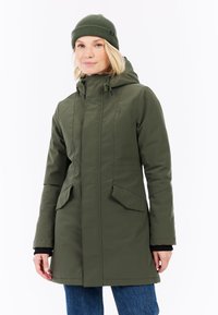 Olivově zelená bunda s kapucí, se dvěma předními kapsami, zipovým zapínáním a detaily se stahovací šňůrkou. Stylizováno s odpovídajícím pleteným čepičkou a černými manžetami.