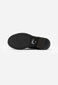 Semelle de chaussure noire avec une adhérence en caoutchouc texturé et un talon arrondi. Présente une légère courbure et une étiquette "37" à l'intérieur. Bords lisses et arrière renforcé.