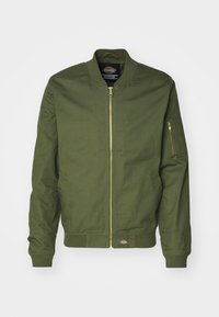 Giacca bomber color verde oliva realizzata in misto cotone, con zip frontale, polsini a costina e tasca laterale con zip. Toppa con logo in fondo.