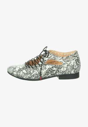 Scarpa stringata in bianco e nero con motivo grafico, tomaia effetto pelle, punta affusolata, tacco piatto e piccole aperture lungo i lati.