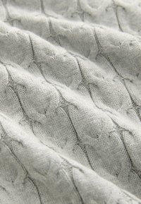 Tissu en maille torsadée de couleur gris clair avec une surface douce et texturée et un motif de tricot en forme de diamant.