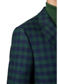 Zielona i granatowa marynarka w kratę z teksturowanej tkaniny, z wykładanym kołnierzem i wyraźnie zbudowanym ramieniem. Zbliżenie na szew ramienia.